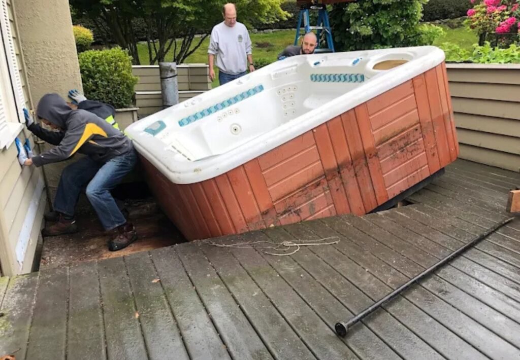 junk removal team pushing out a big hot tub
